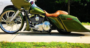 Side picture. Custom olive green bagger motorcycle with a brown leather seat, large front wheel, and low extended saddlebags