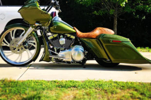 Side picture. Custom olive green bagger motorcycle with a brown leather seat, large front wheel, and low extended saddlebags
